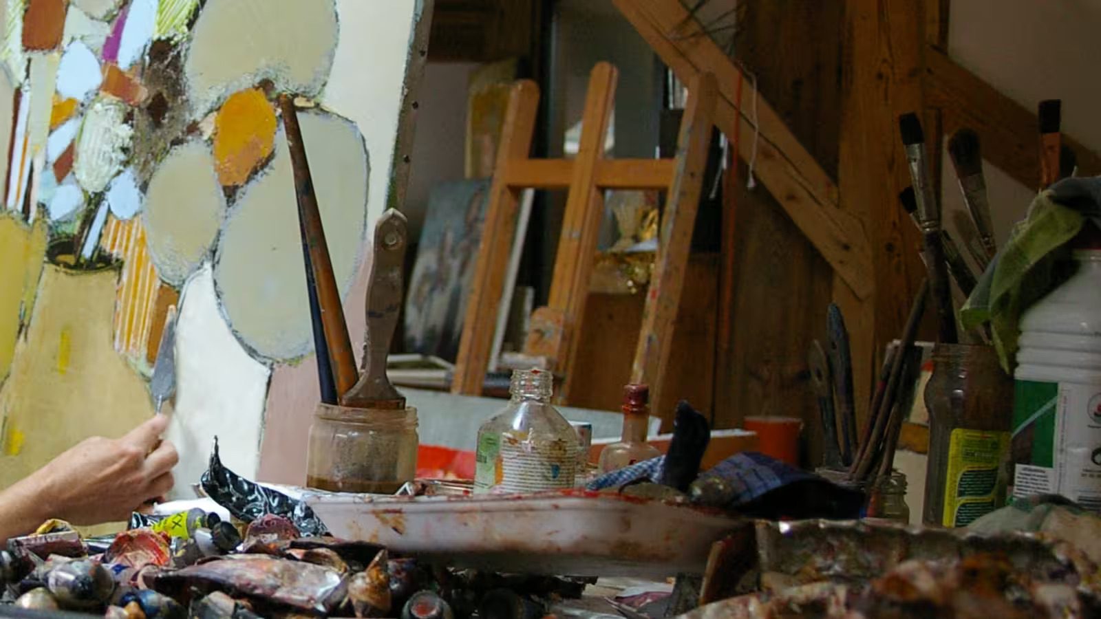 Atelier d’artiste avec pinceaux, tubes de peinture et toile abstraite en cours